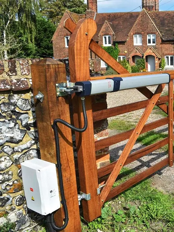 A wooden farm-style gate with an electric opener, a perfect example of the durable Electric & Automatic Gates installed by Gates Wellington.